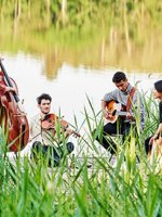 VRK Existenzsicherung – Eine Gruppe junger Menschen sitzt an einem See und spielt auf ihren Instrumenten.