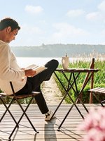VRK Rechtsschutzversicherung – Ein junger Mann sitzt auf seiner Terrasse und liest ein Buch.